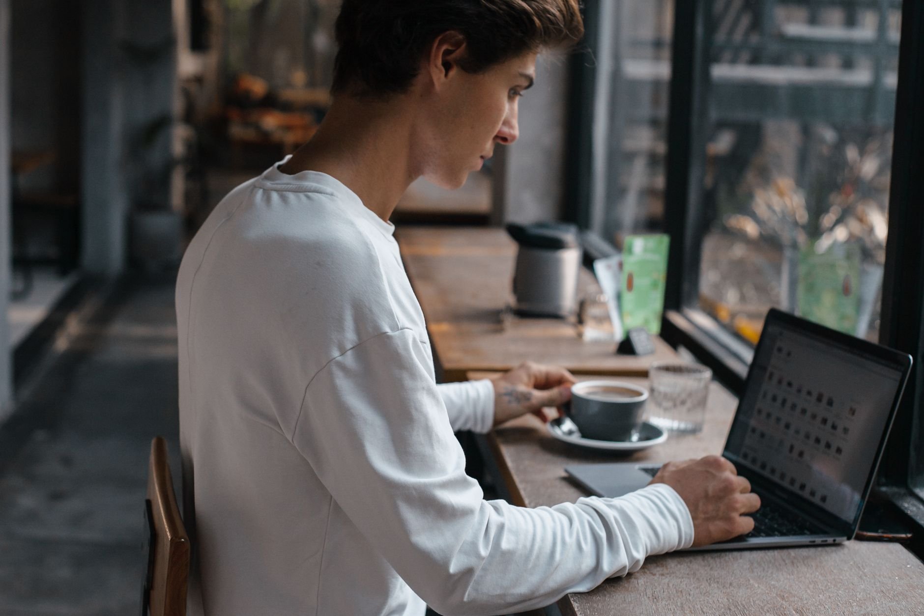 Young man working on a laptop in a café — a professional finding his own way to work